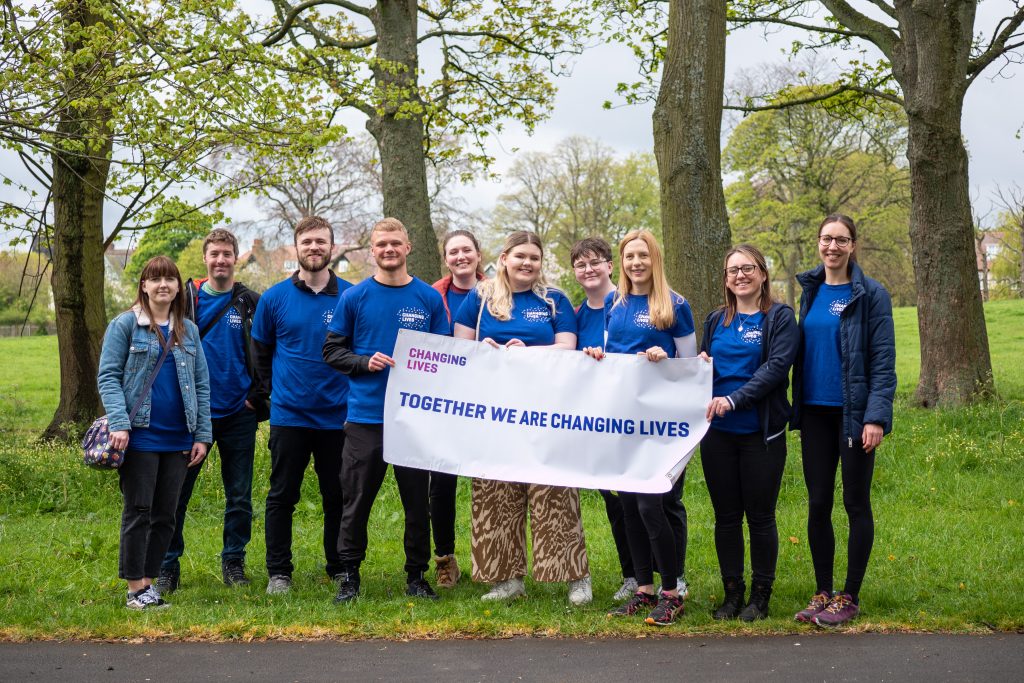 changing lives team holding a banner saying Together We Are Changing Lives